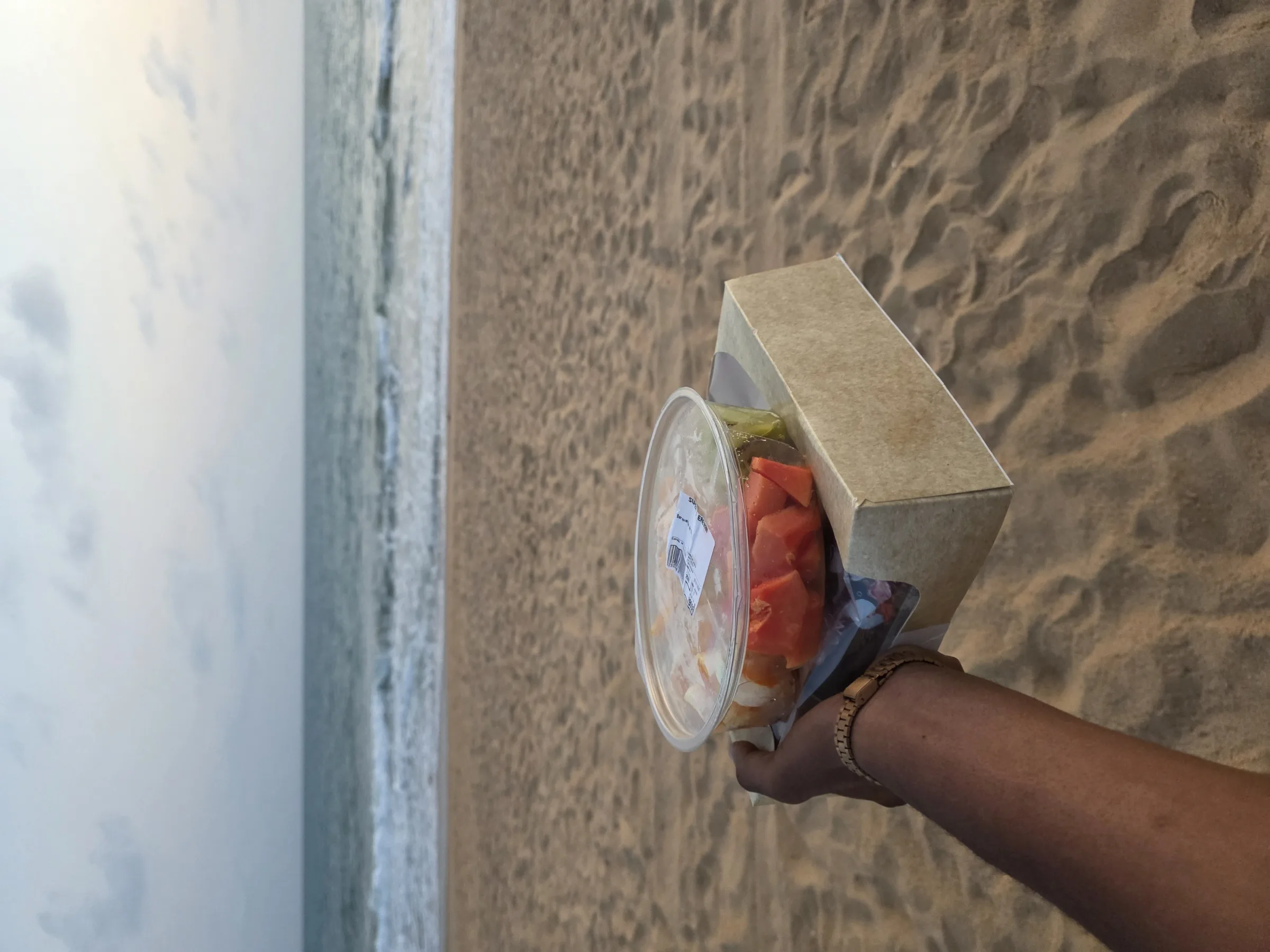 A cold drink held out over the sand