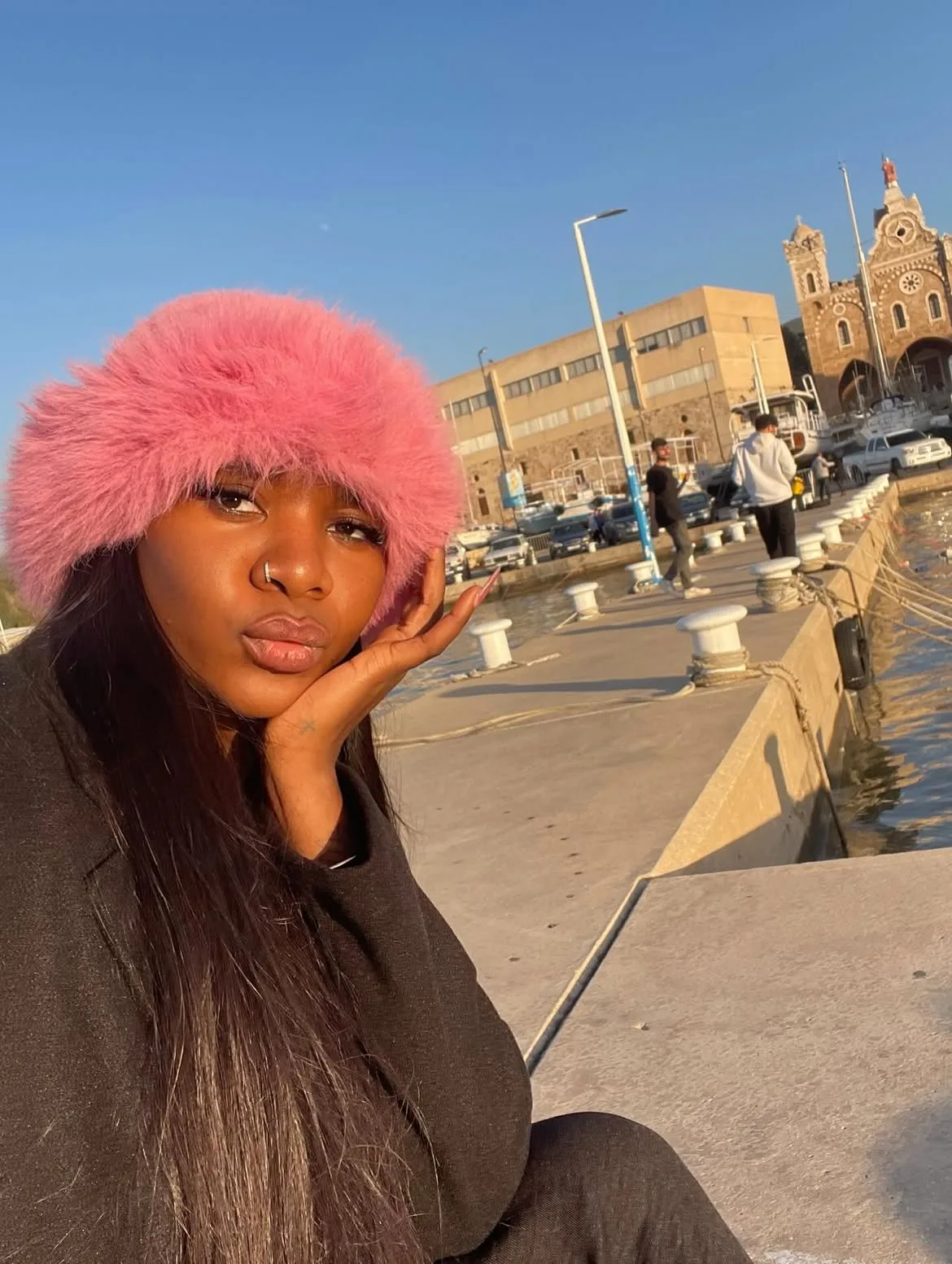 A member in a pink fur hat by the waterfront