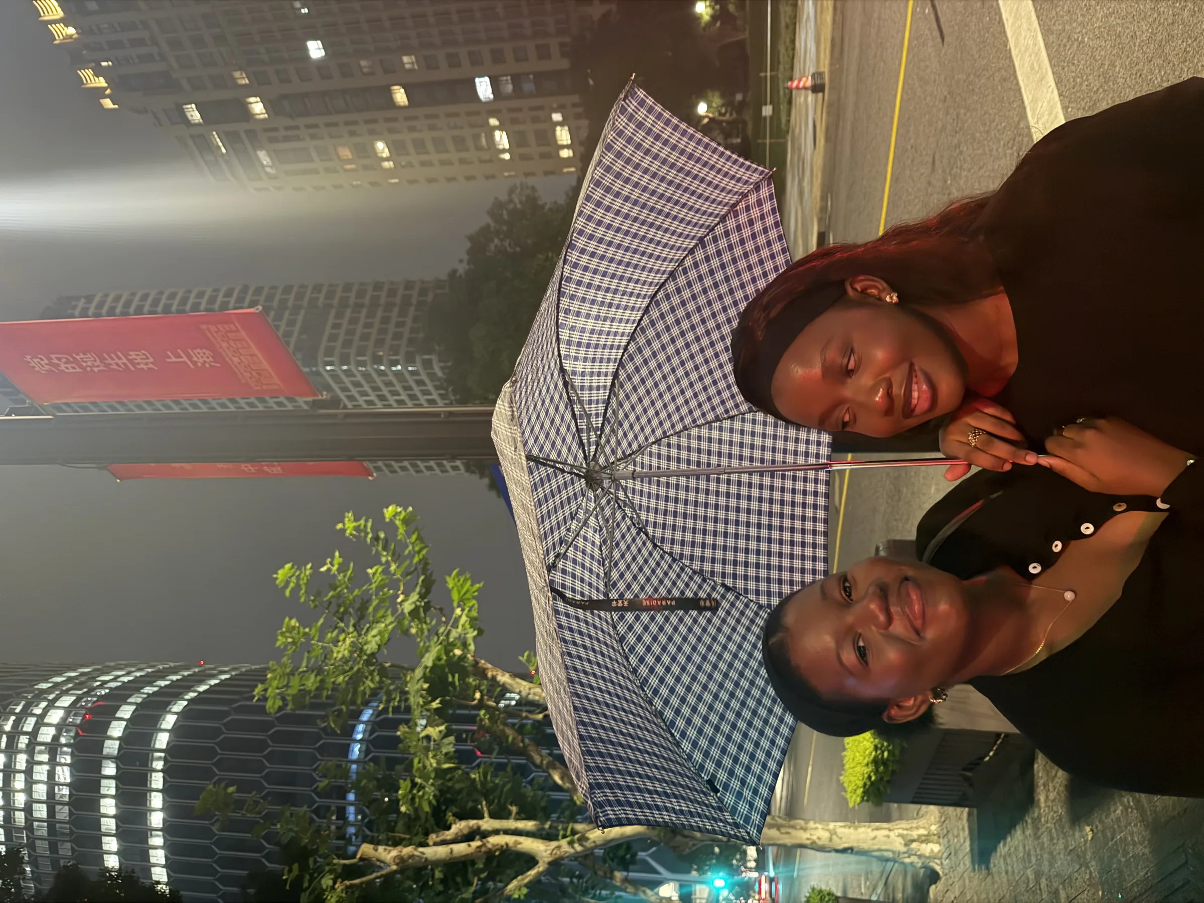 Two members under a patterned umbrella in the evening